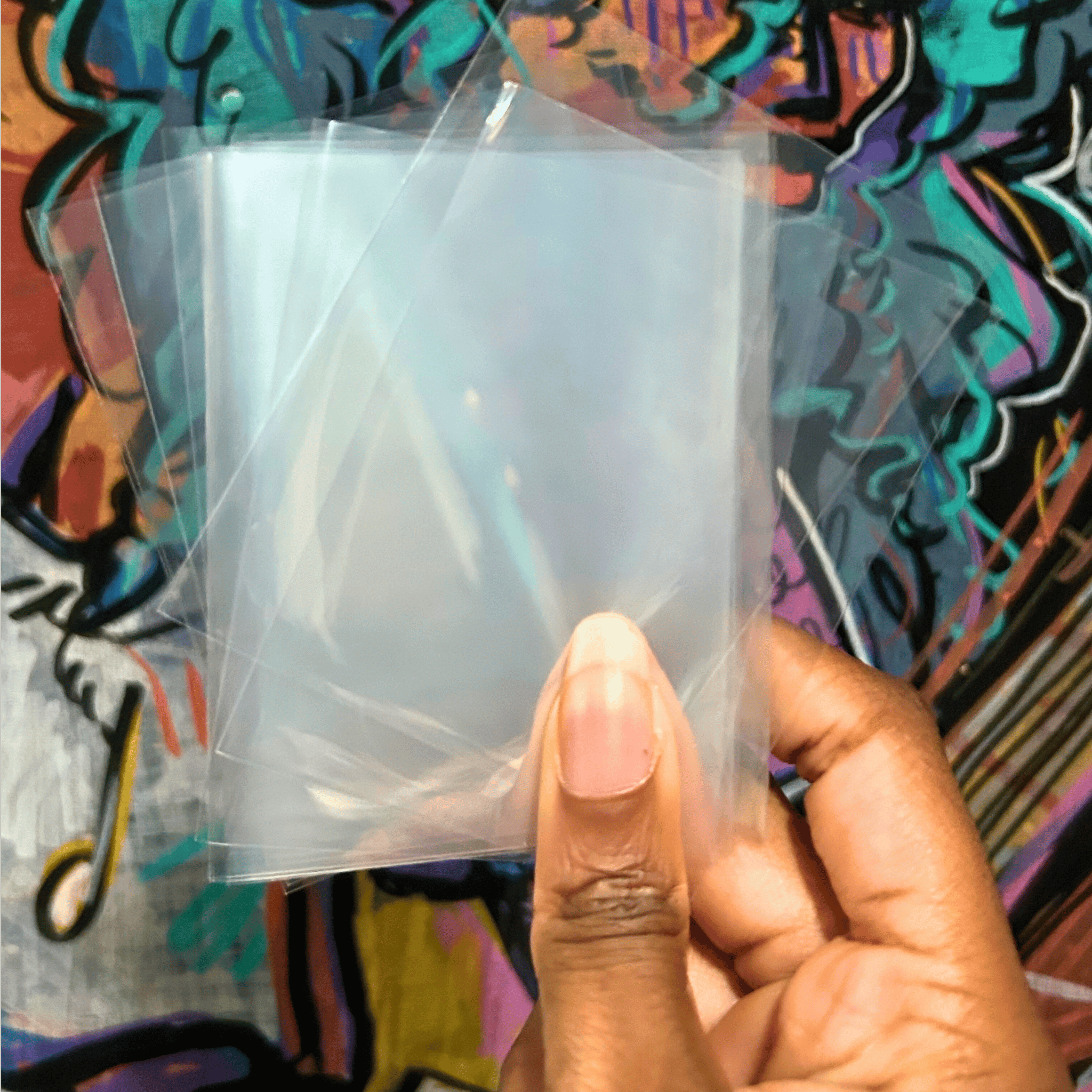 Hand holding a clear plastic sheet against a colorful abstract background