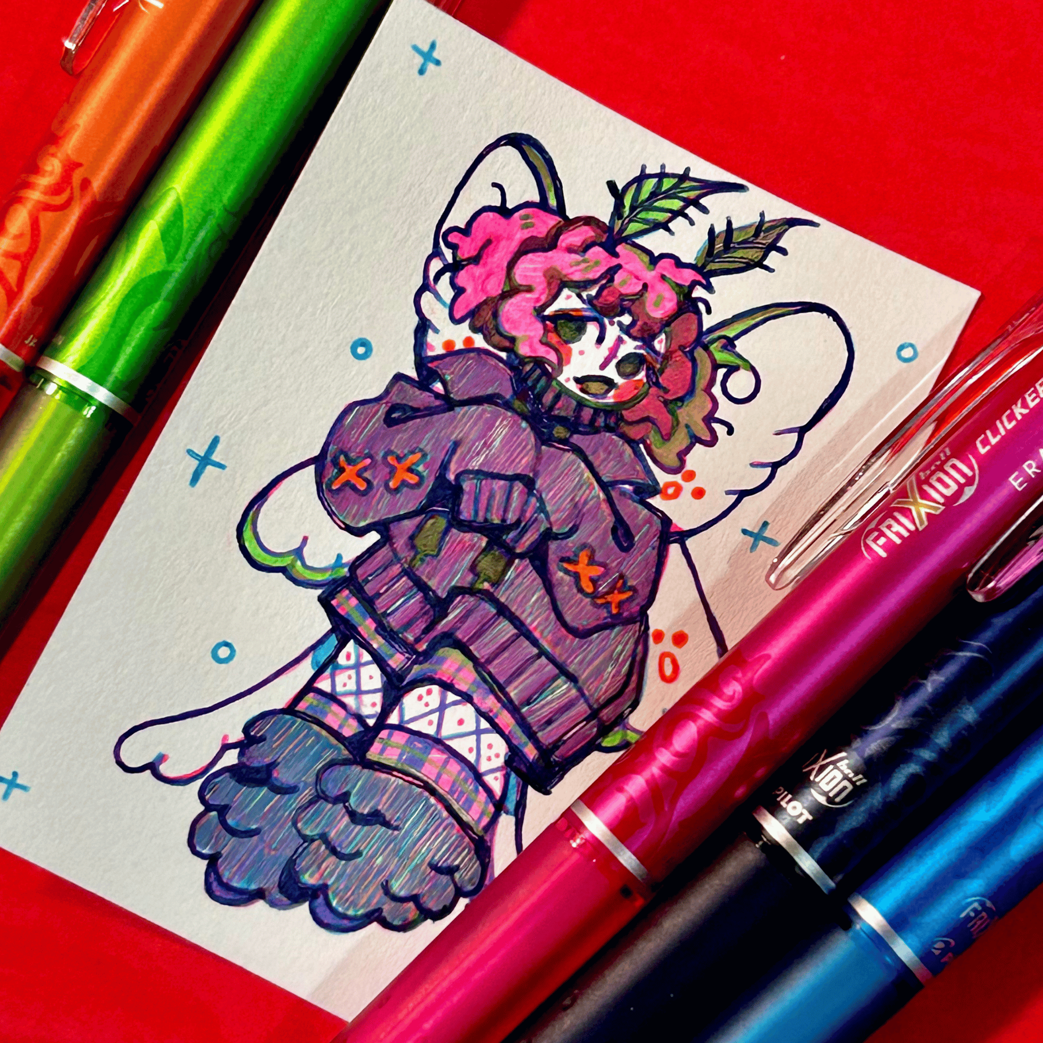 Colorful drawing of a moth girl character on paper with colorful pens on a red background
